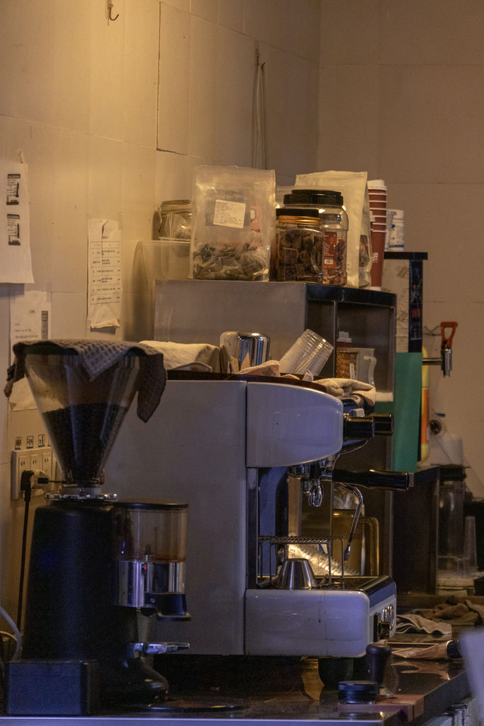 A coffee machine and shelves in a warmly lit interior.
