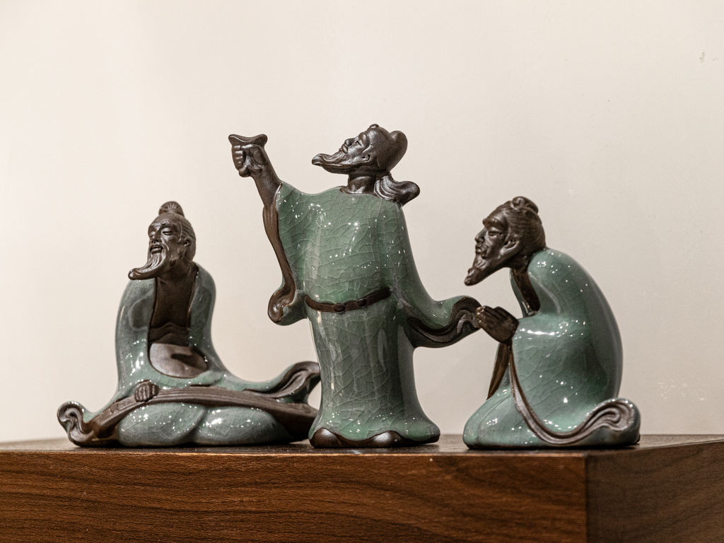 Three green glazed animal figures set against a pale wall.